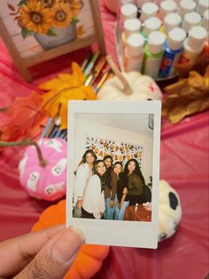 a person holding up a polaroid in front of a table full of arts and crafts