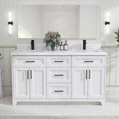 a white bathroom with double sinks and mirrors on the wall, along with potted plants