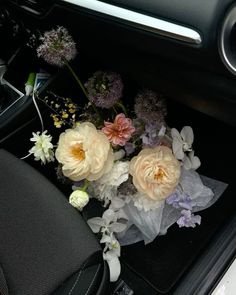 flowers are placed in the center console of a car's trunk area, along with other flowers and foliage