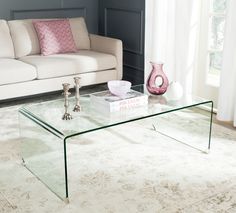 a glass coffee table sitting on top of a white rug in front of a couch