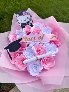 a bouquet of pink and white flowers with a hello kitty graduation sign on it's side