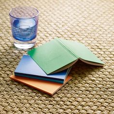 four different colored papers sitting on top of a table next to a glass of water