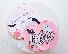 a white plate topped with pink and black paper cut outs next to a tag that says booo