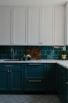 a kitchen with white cabinets and green tile backsplash