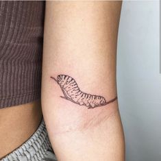 a woman's arm with a small tattoo of a caterpillar