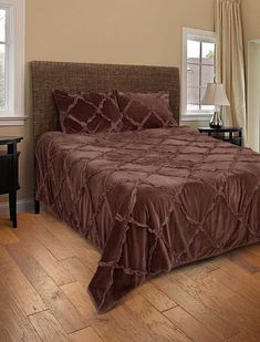 a bed sitting in a bedroom on top of a hard wood floor next to a window