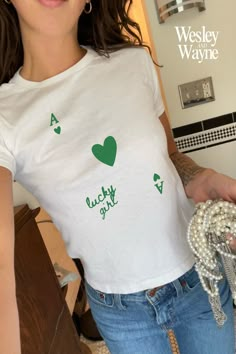 "Looking for a graphic baby tee nostalgic of the 90s? Bring your Y2K outfit dreams to life with our newest St. Patty's Day collection☘️ This classic baby tee will fit like a well-loved favorite from its first wear. Our stylish Gildan 5000B tees feature...  100% USA cotton (Note: Sports Gray color variation features 90% Cotton & 10% Polyester)  Ribbed knit, crew neckline and tear away label  90s style baby tee fit - please reference our size chart for details ✨ PLEASE NOTE: The Gildan 5000B is a \"youth\" t-shirt. Reflective of authentic baby tees of the 90s, the shirt will hit at hip length and may feel looser around the waist than at the bust. Unlike today's crop tops, these are not designed to feel skin tight.  👉🏼 The listing photos reflect the Gildan 5000B garment on a female model wi 90s Shirts Graphic Tees, St Pattys Day Outfit, Minimal Shirt Design, Lucky Girl Syndrome, Coquette Shirt, Baby Graphic Tees, Lucky Shirt, 90s Baby, Y2k Baby Tee