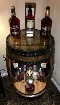 three bottles of whiskey sitting on top of a barrel