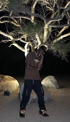 a man standing under a tree talking on a cell phone