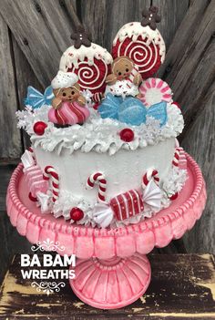 a decorated cake sitting on top of a pink plate next to a wooden fence with candy canes and candies