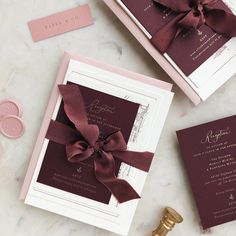 the wedding stationery is laid out on top of the table with its ribbon tied around it