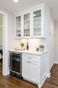 a kitchen with white cabinets and wood flooring is pictured in this image, there are plants on the counter