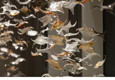 a wind chime hanging from the side of a wall next to a mirror with gold and silver leaves on it