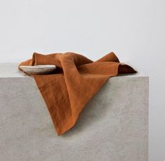 an orange cloth is laying on top of a cement block with a white bowl in the background