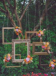 three frames are hanging from strings with flowers on them and one frame is suspended in the air