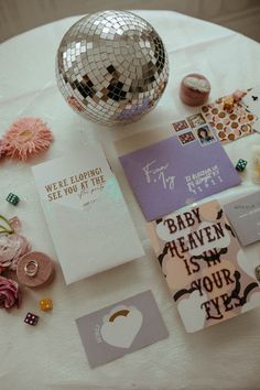 a table topped with lots of different types of cards and confetti next to a disco ball