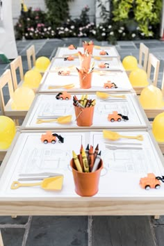 a long table set up with construction themed place settings and yellow balloons in the background