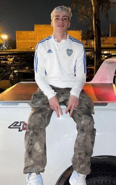 a man sitting on the back of a white truck in front of a parking lot