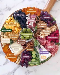 a platter filled with different types of cheese and meats on a marble counter top