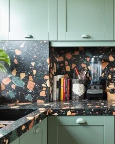 a kitchen with green cabinets and marble counter tops