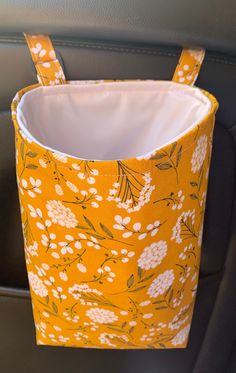 the inside of a car seat with a yellow and white flowered bag hanging from it's side