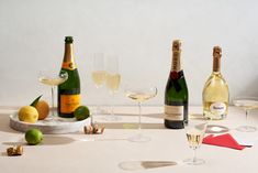 several bottles and glasses of wine on a table with lemons, limes and corks