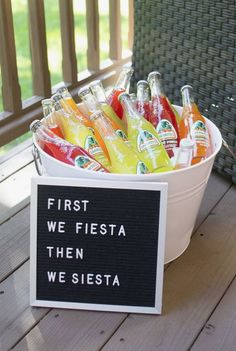 a white bucket filled with lots of different types of drinks next to a sign that says first we fiesta then we siesta