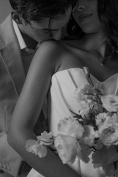 a man and woman embracing each other with flowers in their lapel, black and white photo