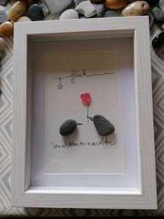 two small rocks in a white frame with the words i love you written on them