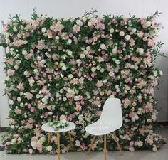 two white chairs sitting in front of a wall covered with pink and white flowers,