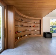 a curved wooden shelf in the middle of a room with glass doors and shelves on both sides