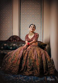 a woman sitting on top of a couch wearing a dress and headpiece with an intricate pattern