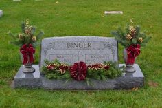 the headstone of bingner is adorned with red bows and holly wreaths for christmas