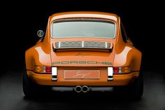 an orange porsche parked in a dark room