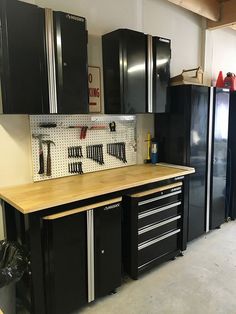 a garage with lots of black cabinets and tools on the counter top in front of it