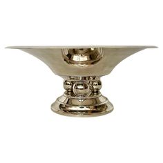 a silver bowl with two handles on it's sides and a circular base in the middle