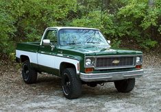 a green and white truck parked in the woods