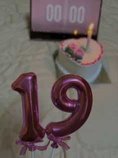 a pink number one cake on a table with a birthday candle in the shape of an 11