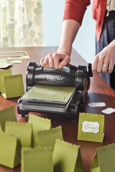 a person is using a machine to cut out pieces of paper on a wooden table