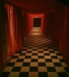 the hallway is lined with black and white checkered flooring, along with red drapes