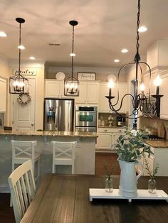 a kitchen with a wooden table and white chairs next to an island in the middle