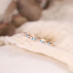 a close up of a ring on a white blanket with a teddy bear in the background