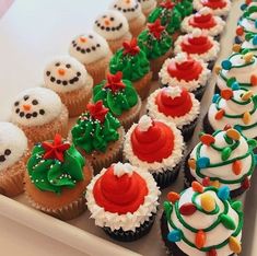 cupcakes decorated with frosting and decorations are lined up on a white tray