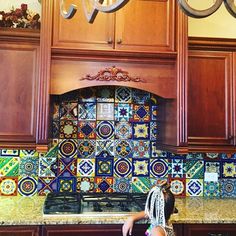 a woman standing in front of a stove top oven under a chandelier over a kitchen counter