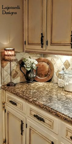 a kitchen with white cabinets and granite counter tops, an old - fashioned tea kettle on the island