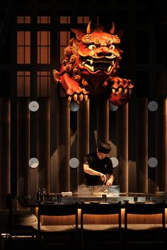 a man standing in front of a table with a dragon head hanging from the ceiling