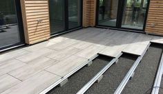 an outdoor patio with wooden siding and sliding glass doors on the outside, surrounded by stone tiles