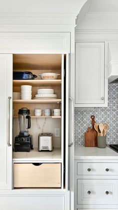 an open cabinet in a kitchen with white cabinets