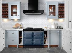 a stove top oven sitting inside of a kitchen next to white cupboards and drawers