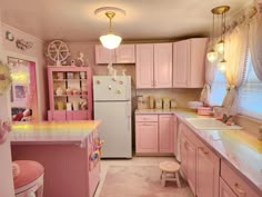 a pink and yellow kitchen with lots of counter space in the center, along with an ice cream colored refrigerator